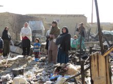 Refugees in the Chaman e Babrak camp stand amid the rubble